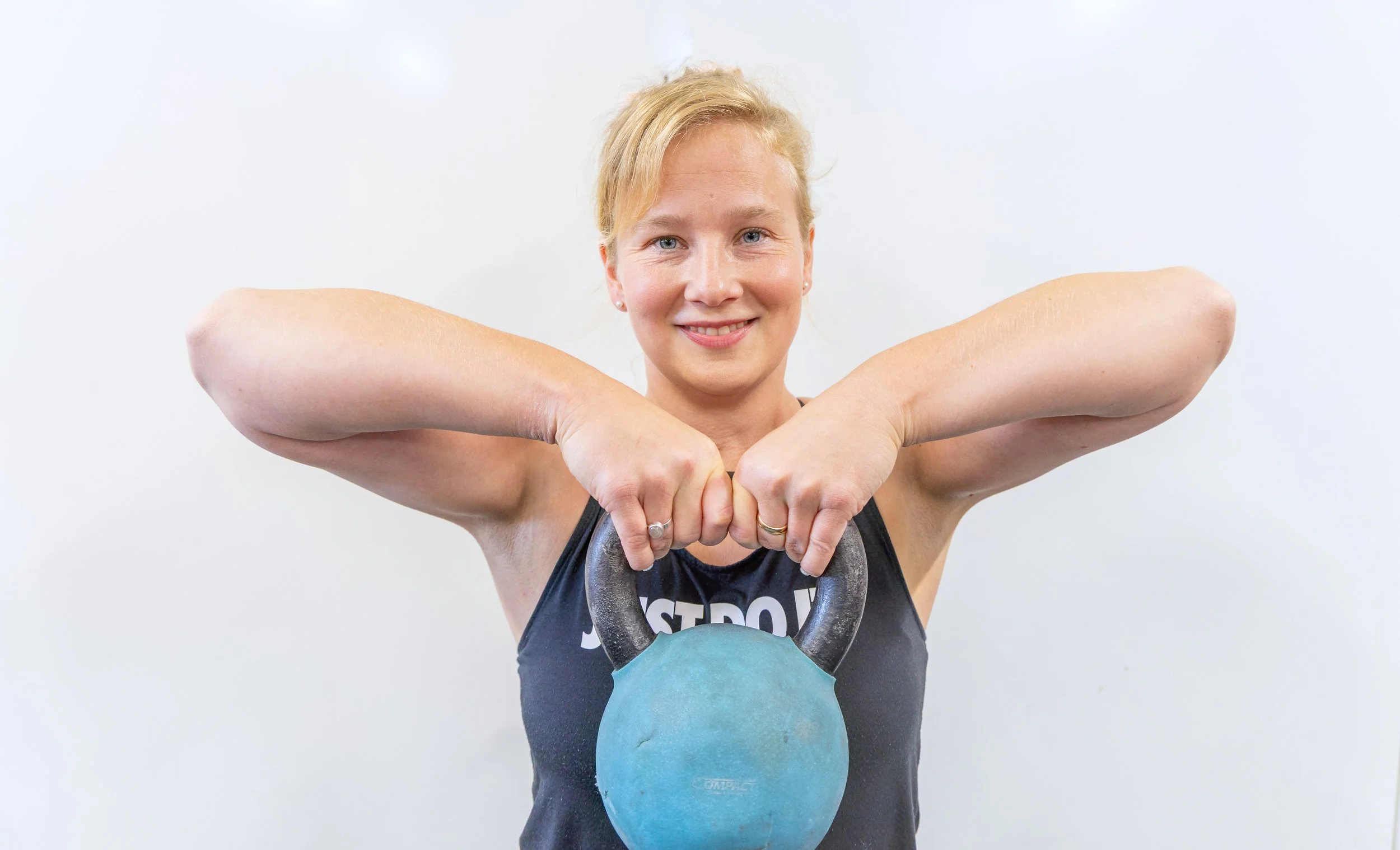 Nainen pitämässä sinistä kahvakuulaa. Niina Haverisen liikuntapalvelut.