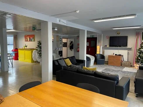 Een gemeenschappelijke lounge met zithoeken, een televisie, kerstversiering en kleurrijke meubels.