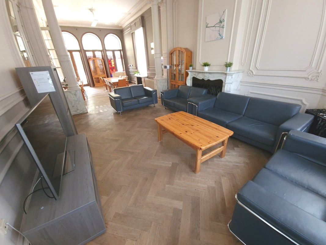 Een luxe woonkamer met hoge ramen, banken, een houten salontafel, een open haard en decoraties.