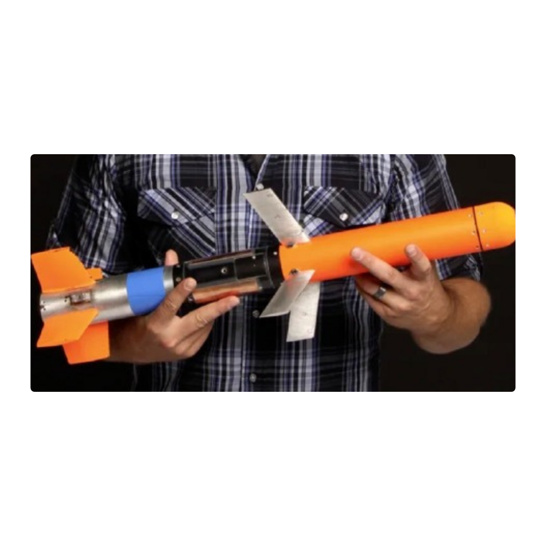 Person holding a model rocket with an orange body, blue nose cone, and black details, against a black background.