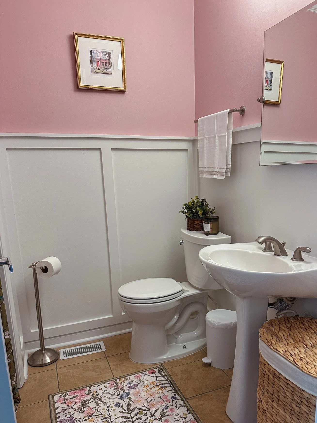 Powder room with white tall frame wainscoting and soft pink walls above, built by Cardinal Custom Finishes in Cary, NC