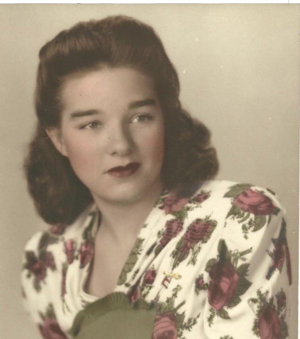 A photo of Nan's Nan. She wore a half up hairdo, dark red lipstick and a rosy blush on her cheeks. She was in a floral printed white dress