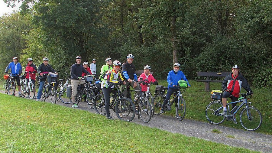 Gruppe von zehn Fahrradfahrern, die an einem Weg im Park stehen.