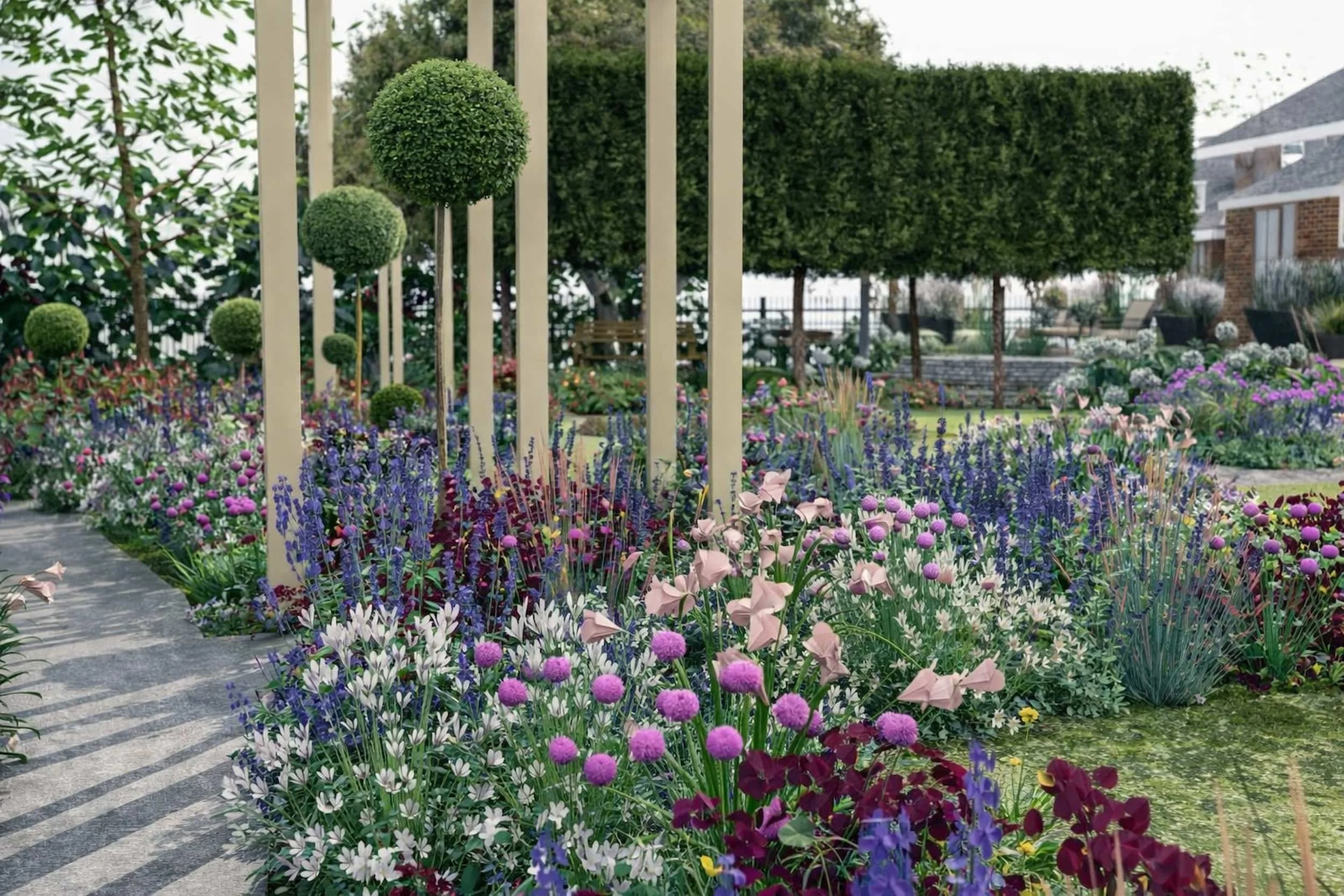 Country side large garden with curved path ways, wooden timber archways, topiary lollipop trees and cottage style planting. Pink, purple and white