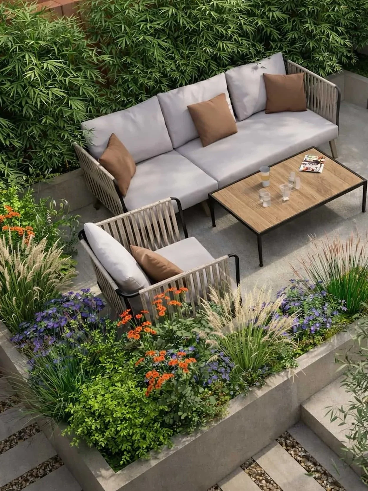 Contemporary garden seating area with a neutral outdoor sofa and armchair set around a wooden coffee table, surrounded by layered planting of grasses, flowering perennials and evergreen screening.