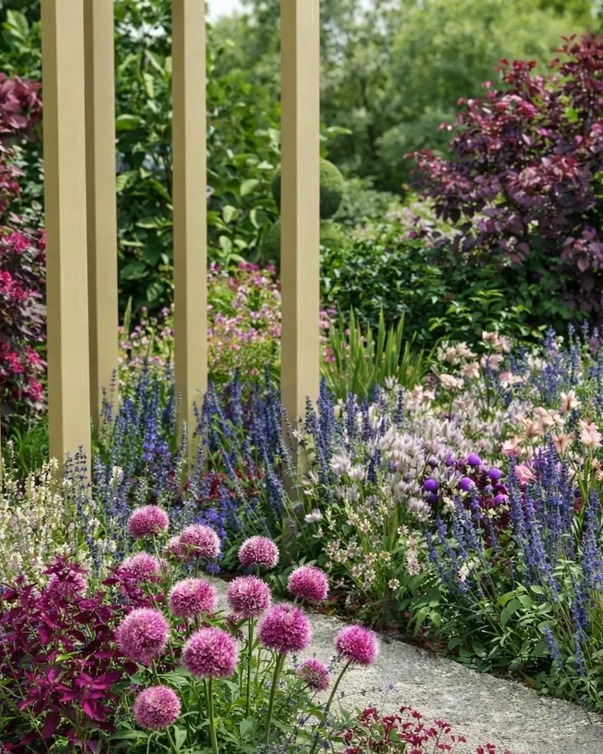Close up of wooden archway with lots of planting. Cottage style planting and lollipop topiary tree in the background. Planting is purple, white and pink with green foliage