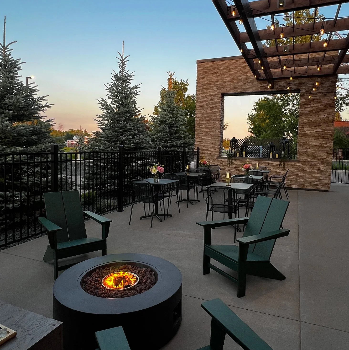 outdoor patio with a firepit and patio furniture and bistro lights hanging