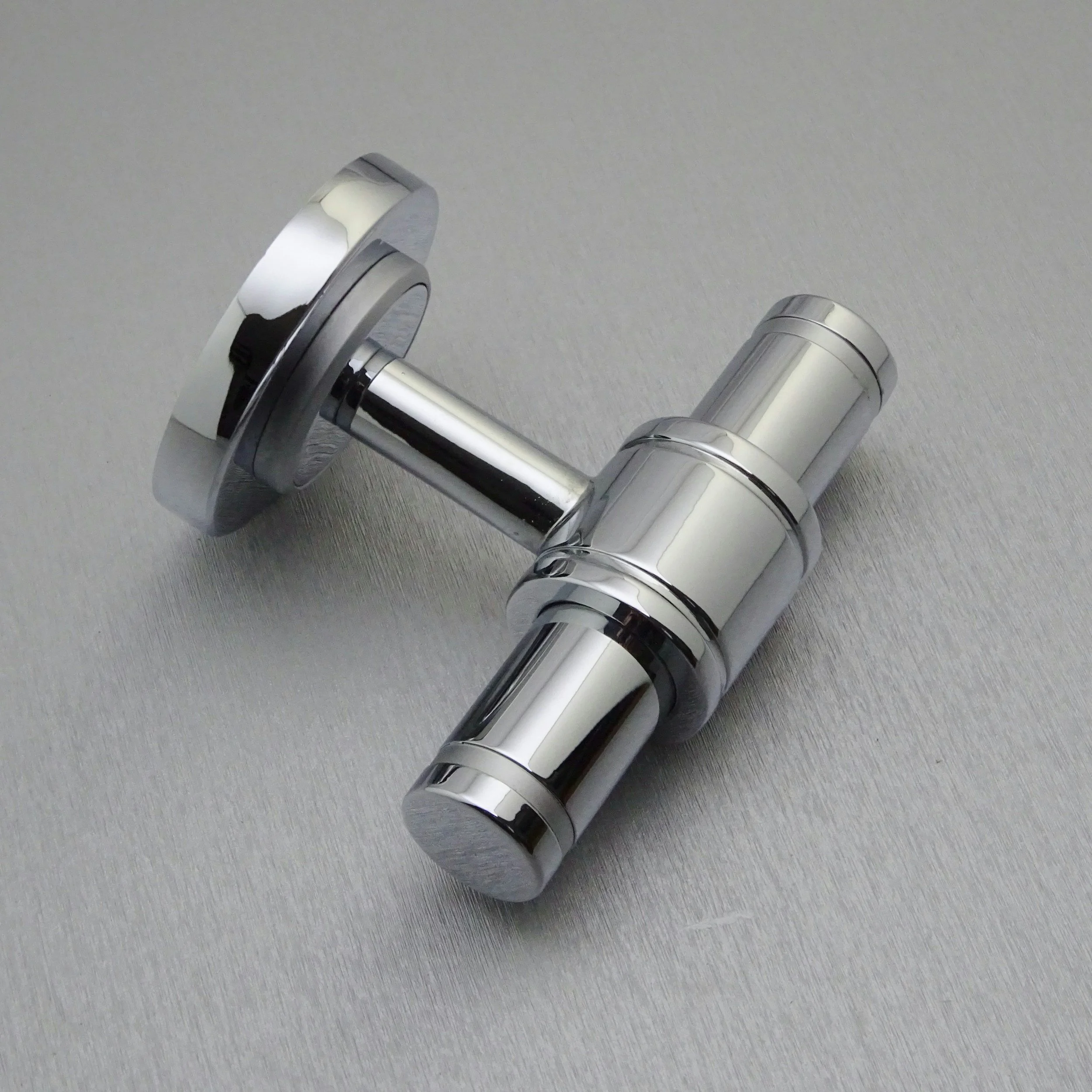 A shiny, silver-colored hair trimmer attachment lying on a gray surface.