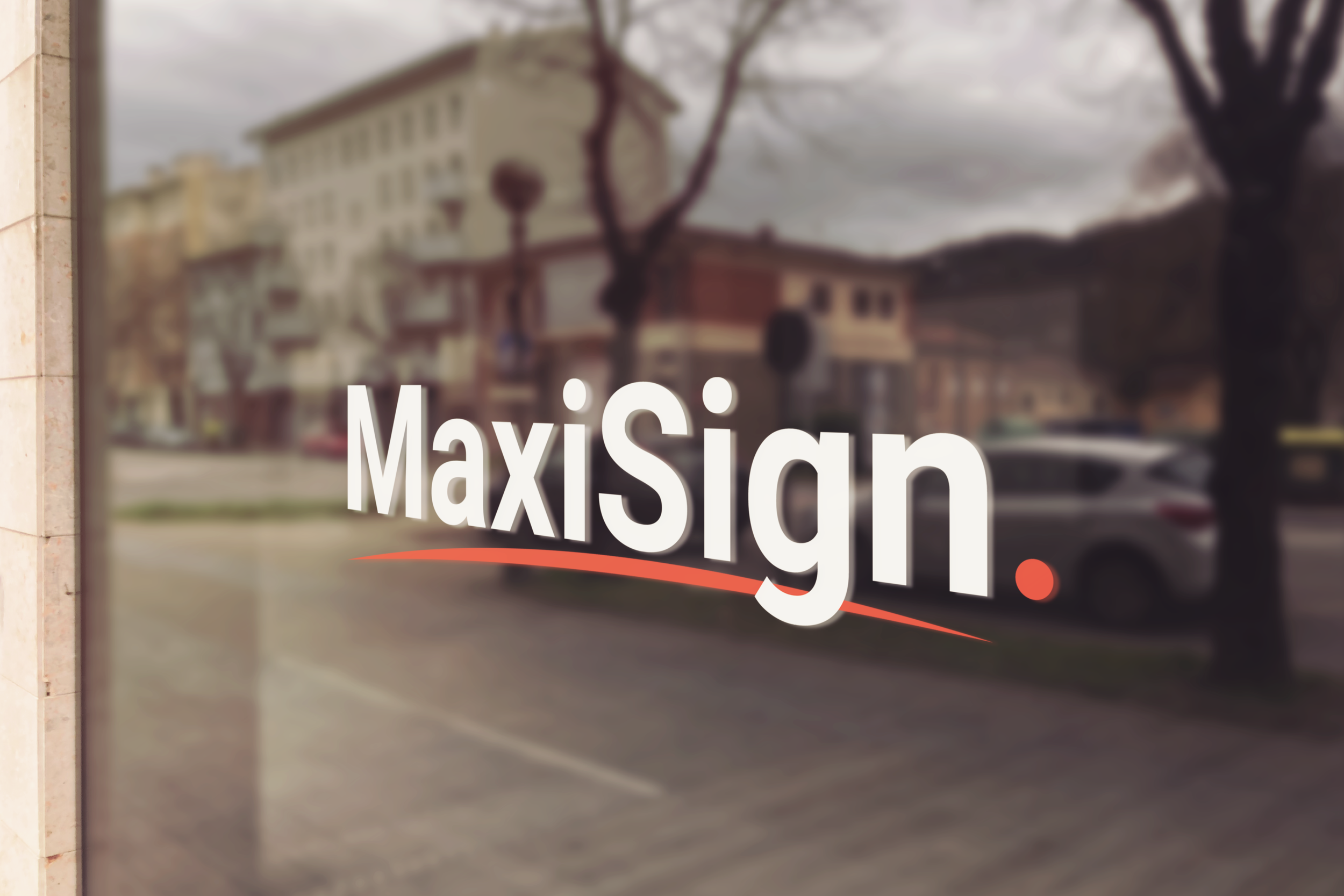 Vitrine de magasin avec le logo 'MaxiSign' écrit en blanc et un fond flou montrant une rue avec des arbres et des voitures