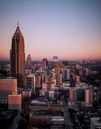 Atlanta skyline at sunset with prominent skyscraper and city buildings.
