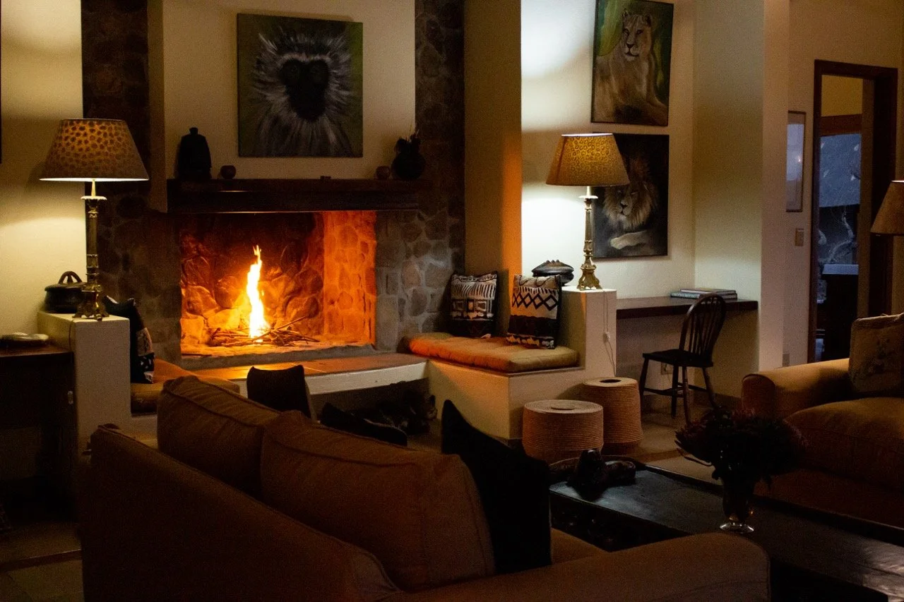 Cozy living room with a lit fireplace, two table lamps, and animal portraits on the walls.