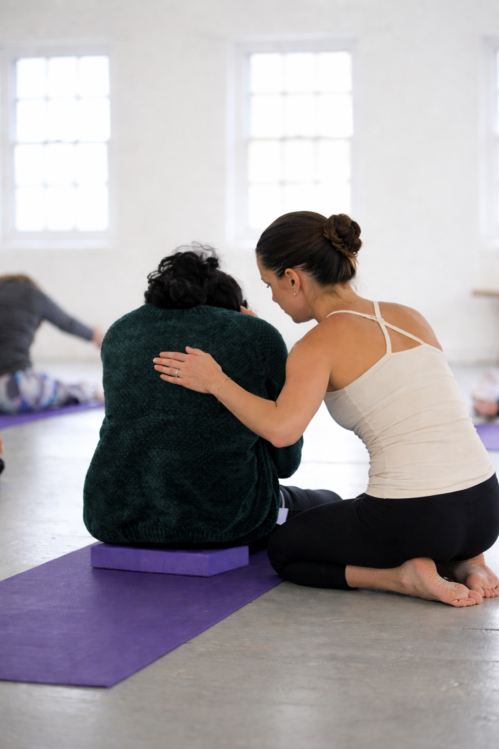 Yoga instructor assisting participant in class.png