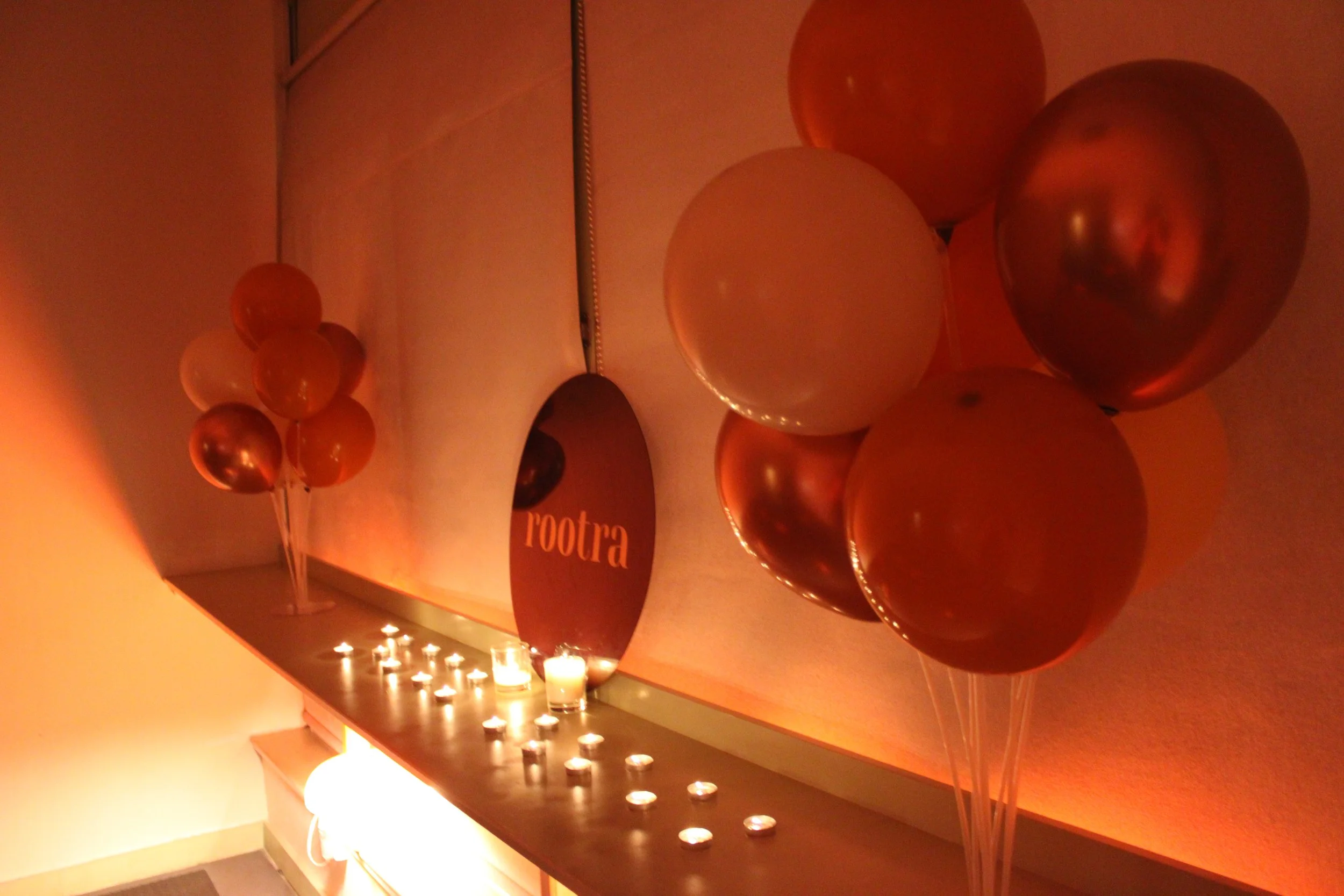 Decorative balloons and tealights on a table inside a dimly lit room.