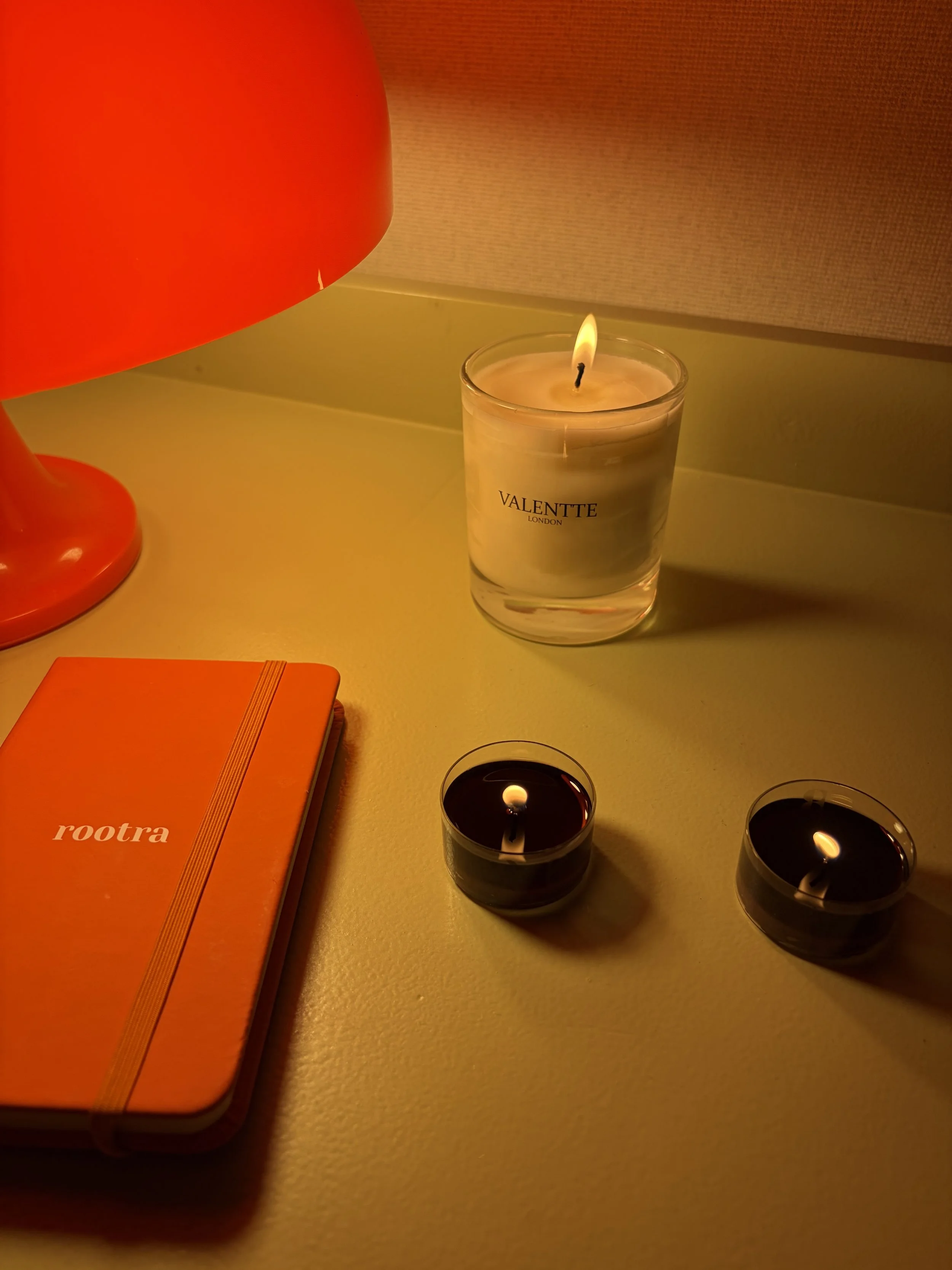 Two people sitting at a white table, each holding a cup of coffee or tea, with a window in the background.