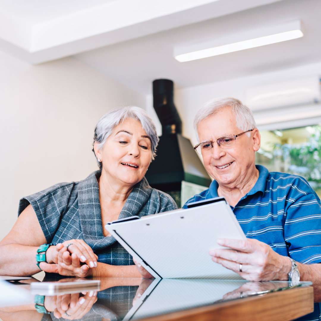 Elderly couple looking at a tablet together in a bright kitchen.