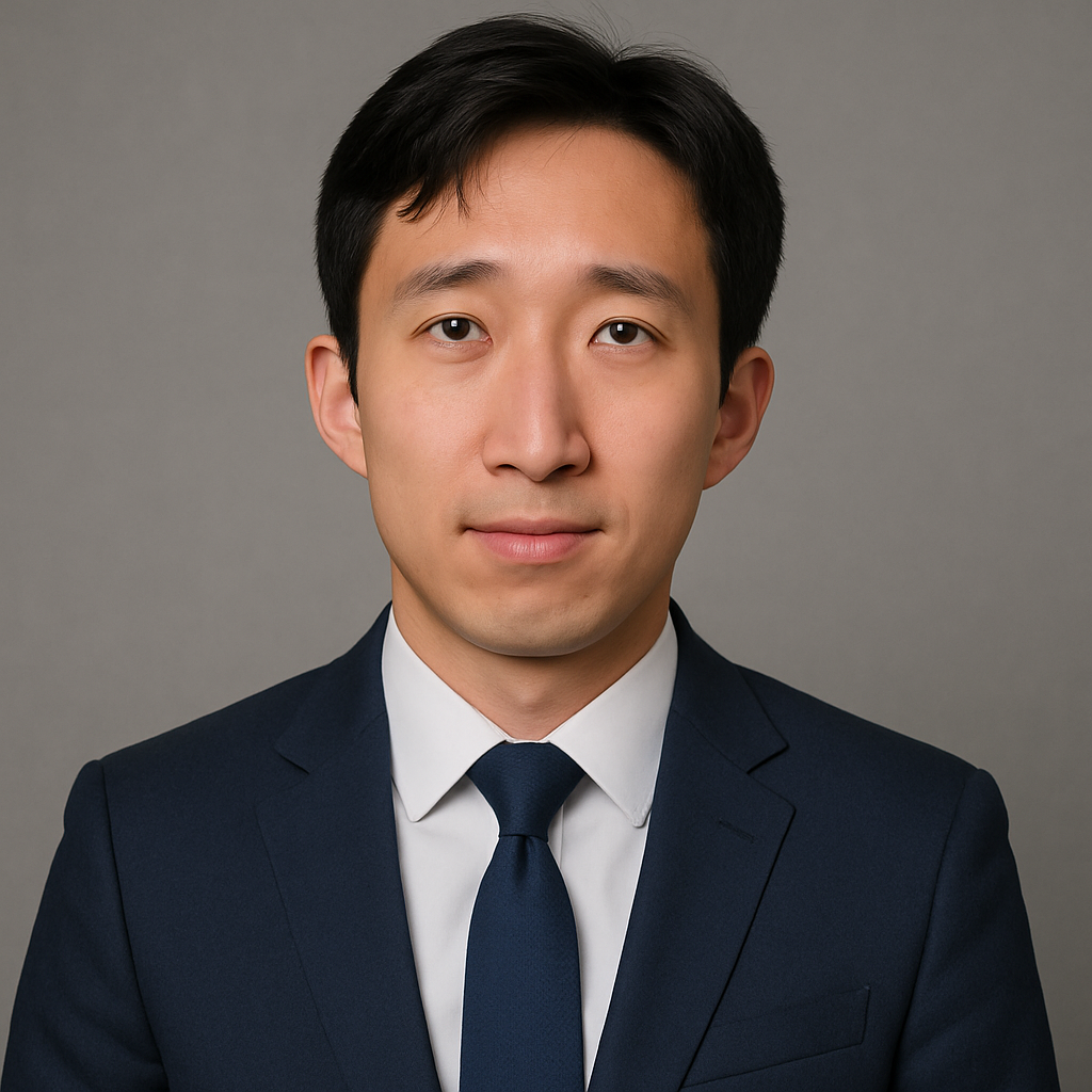 Professional headshot of a young man in a dark suit, white shirt, and navy tie, against a gray background.