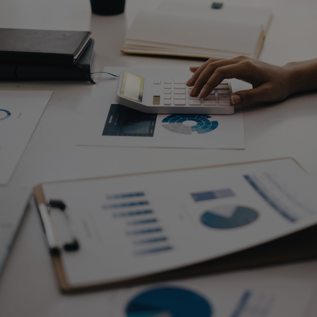 Person working on financial documents with charts and a calculator on a desk.