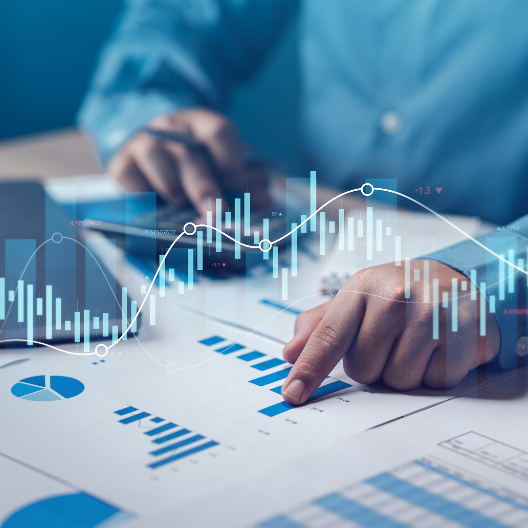 A person in business attire examining financial charts and graphs on paper, with overlay of digital stock market data and line graphs.