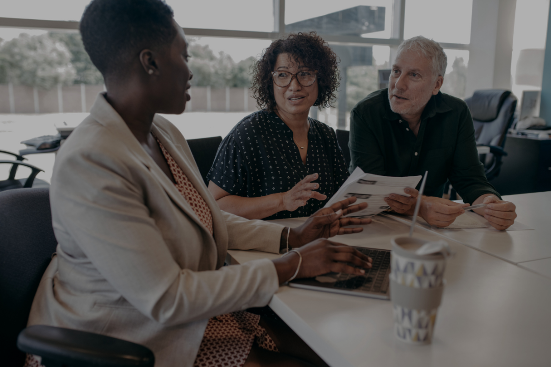 Three people having a discussion at a conference table in an office
