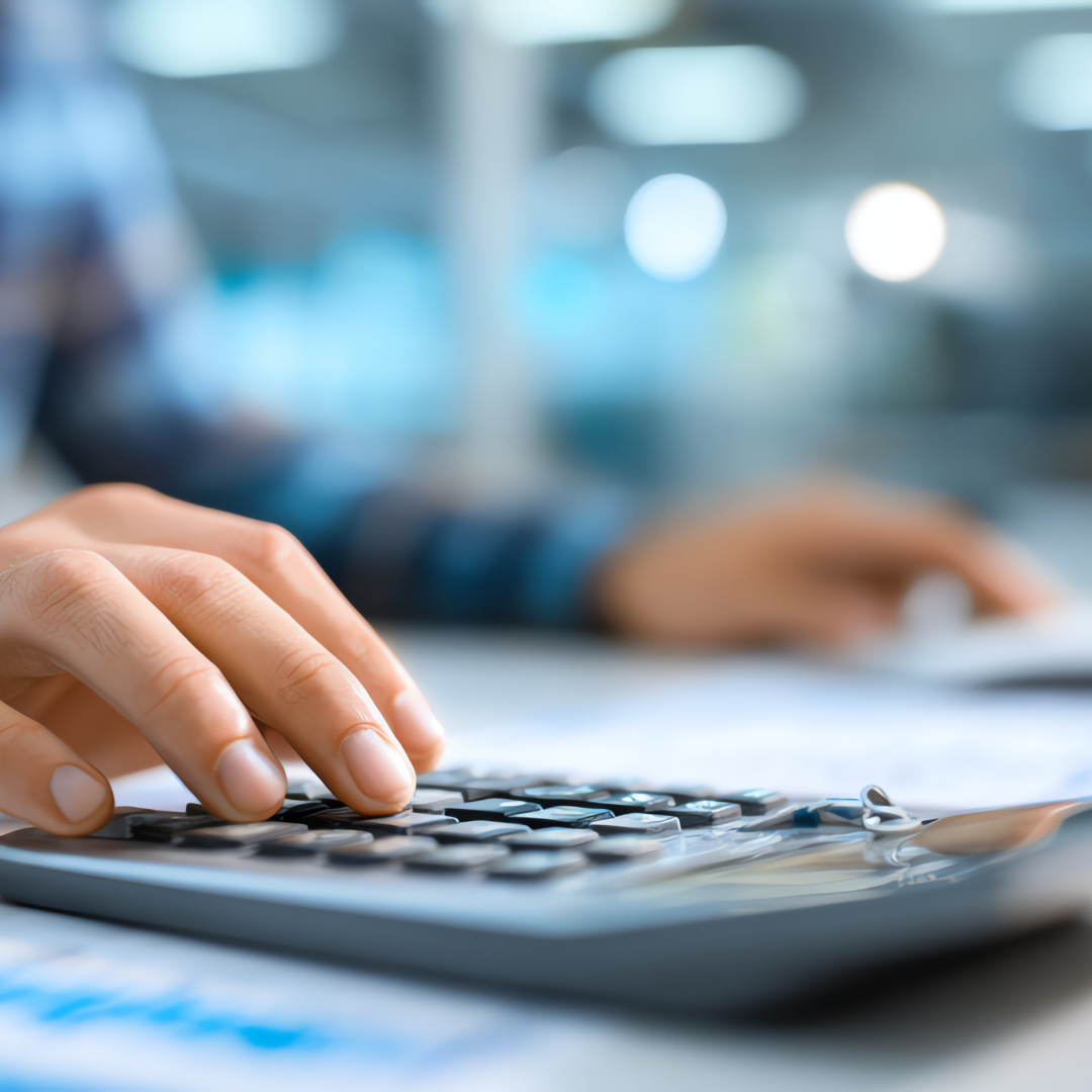 Close-up of a person's hand pressing buttons on a calculator with a blurred background.