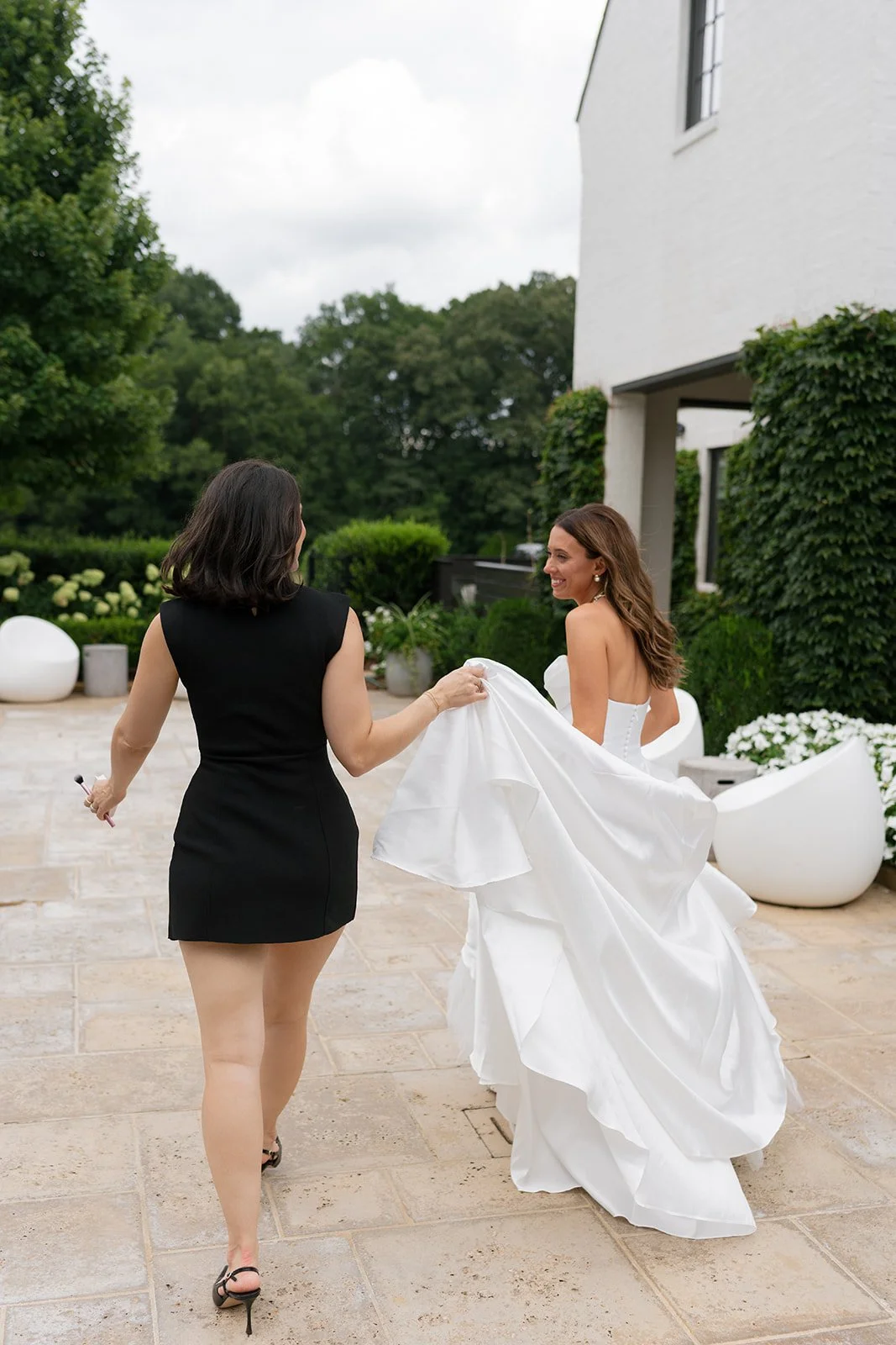 Bride walking with Carly Marie who carries the train of her wedding dress