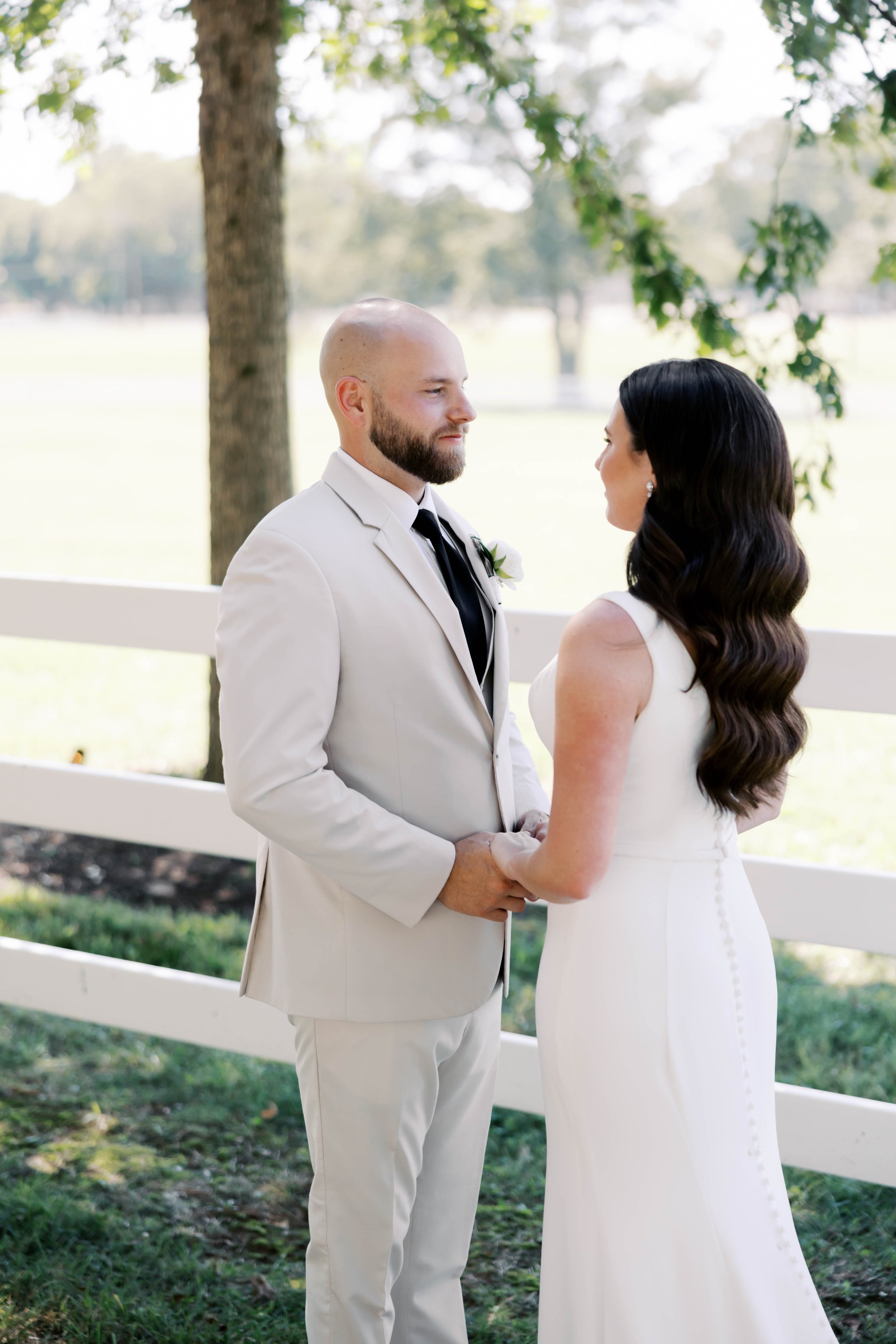 A woman wearing a white wedding dress is standing with her husband after getting married. She has brown hair and is styled in glam waves. Bridal hair and makeup by professional makeup artist, Carly Amico of Carly Marie Artistry, a makeup artist in Ch