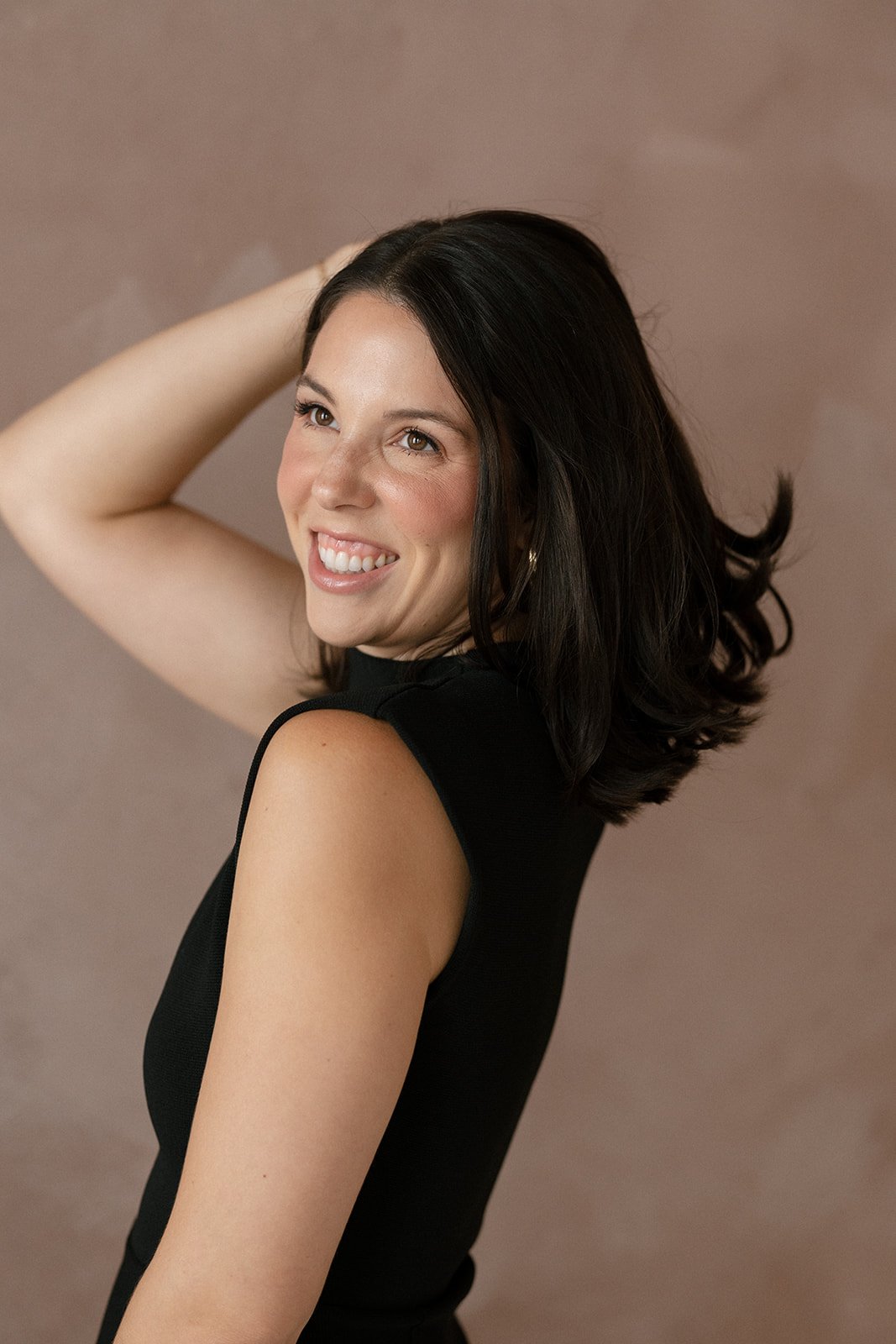 Carly Marie smiling confidently in black dress, hair swept to the side