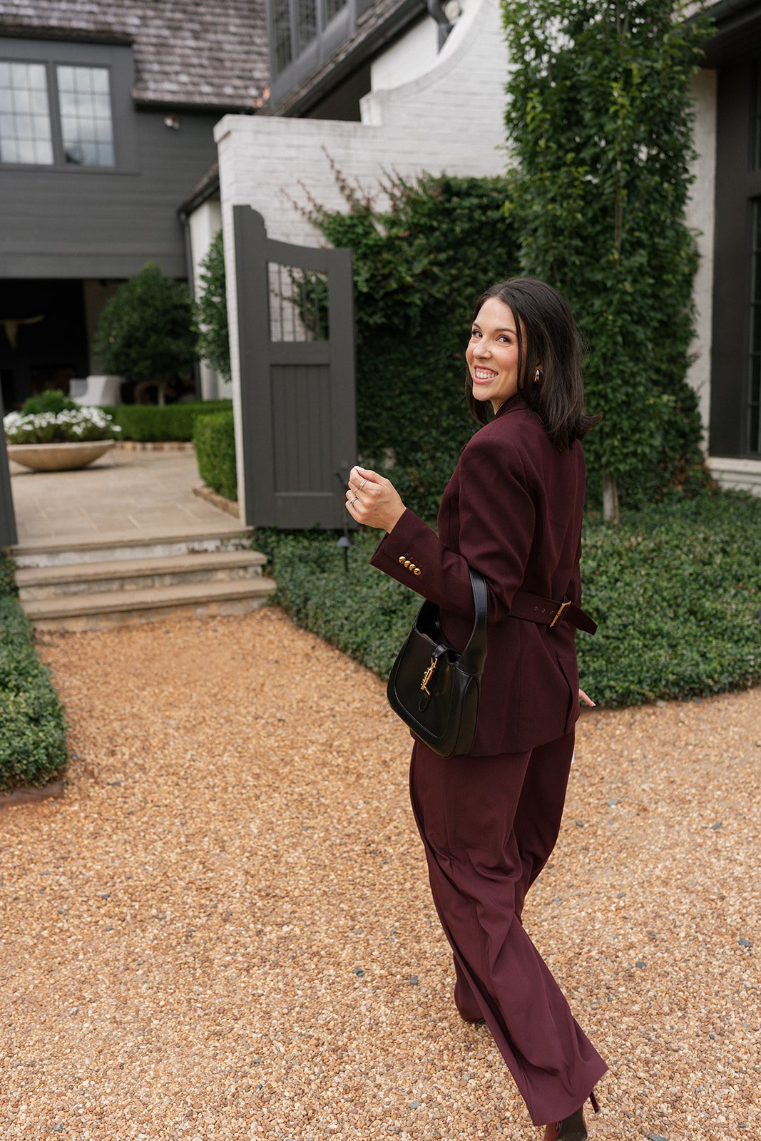 Candid walking shot of Carly Marie in burgundy suit smiling, Charlotte NC makeup artist