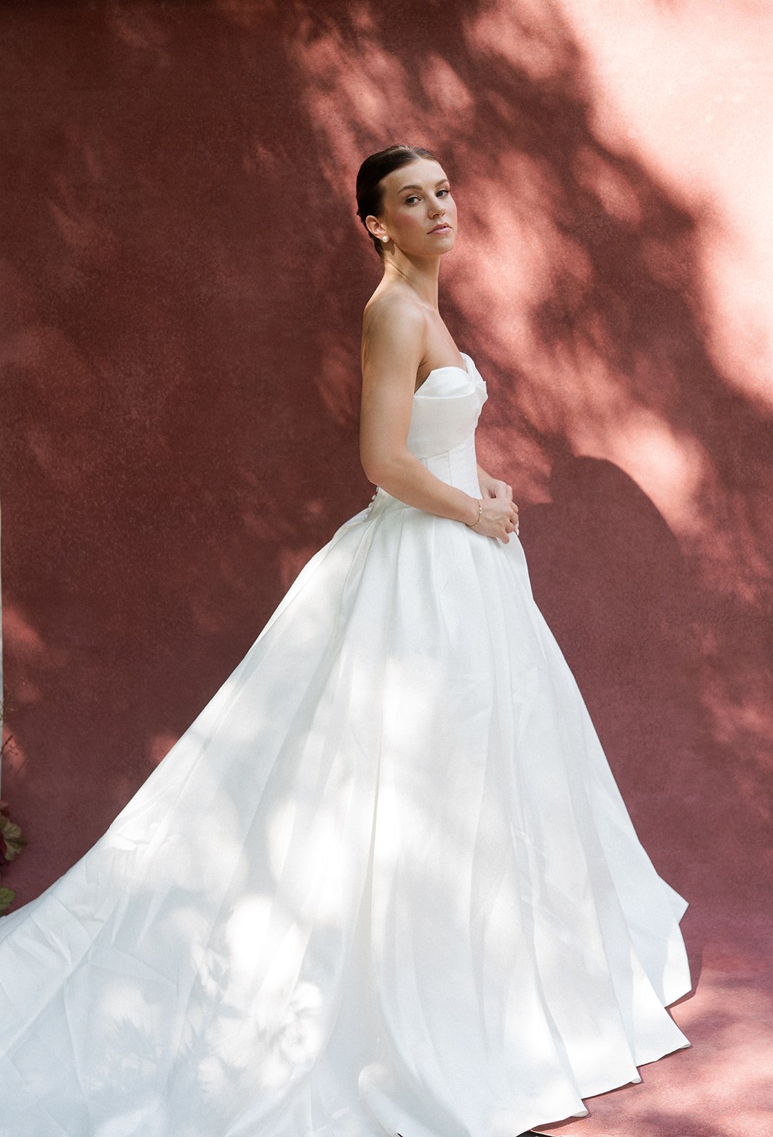 A woman in a white wedding dress posing for a photograph. Her hair is in a slick back bun and she has a soft glam bridal makeup look. Bridal hair and makeup by professional makeup artist, Carly Amico of Carly Marie Artistry, a makeup artist in Charlo