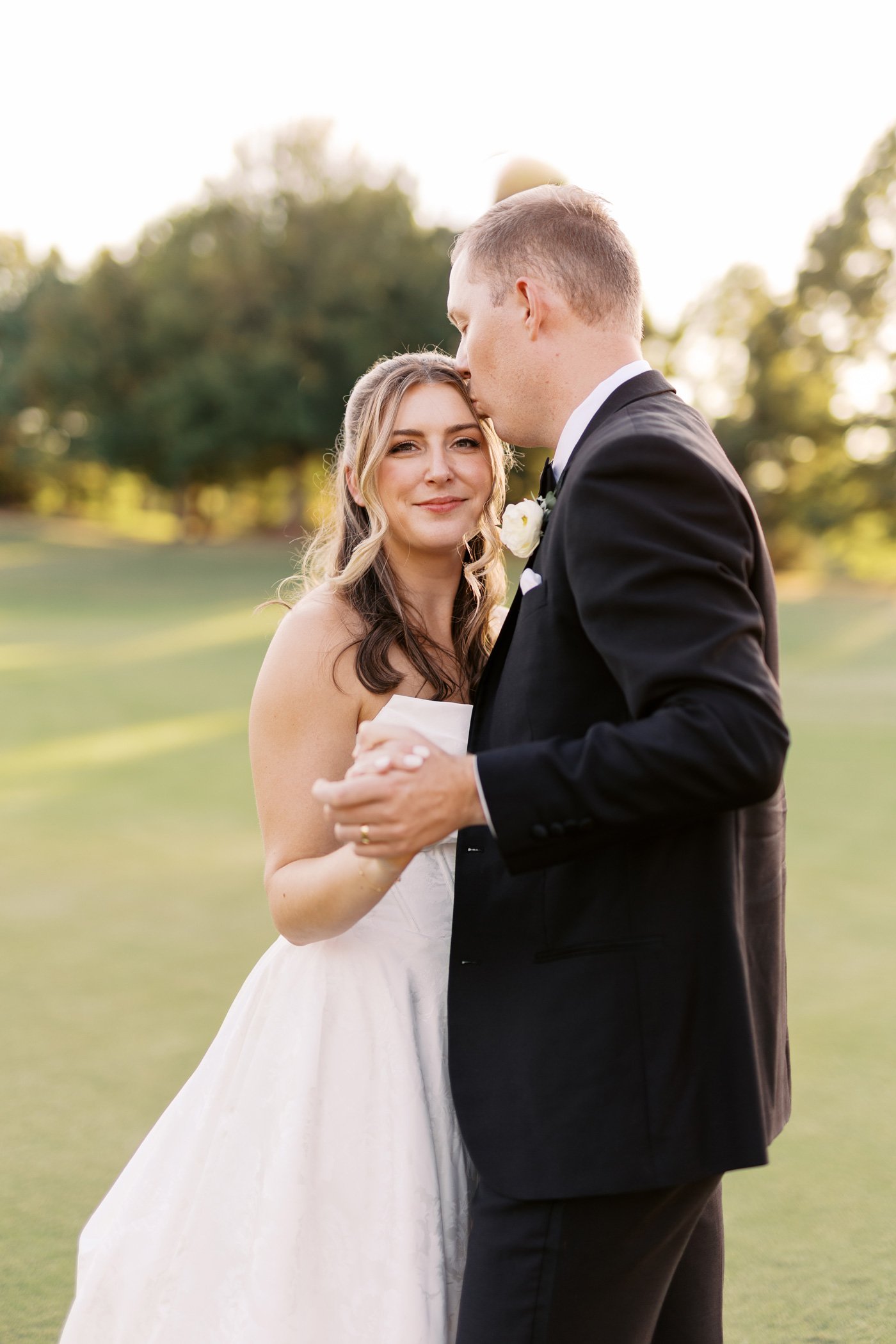 Bride and groom dancing on the lawn with soft golden light and natural wedding makeup by Carly Marie