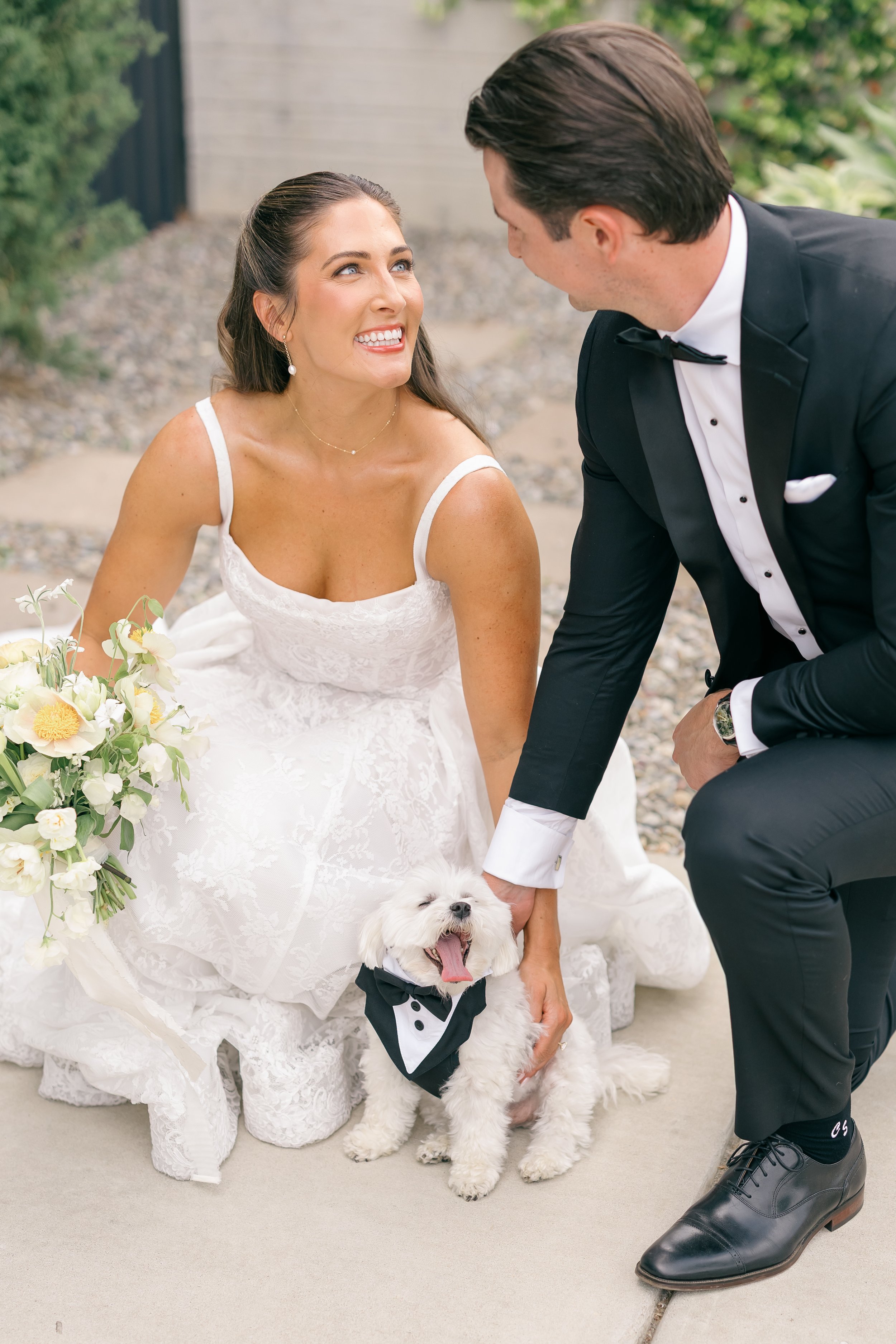 A bride in a white dress with her husband. She has a half up half down bridal hairstyle. Her makeup is a soft glam makeup style that enhances her features.
