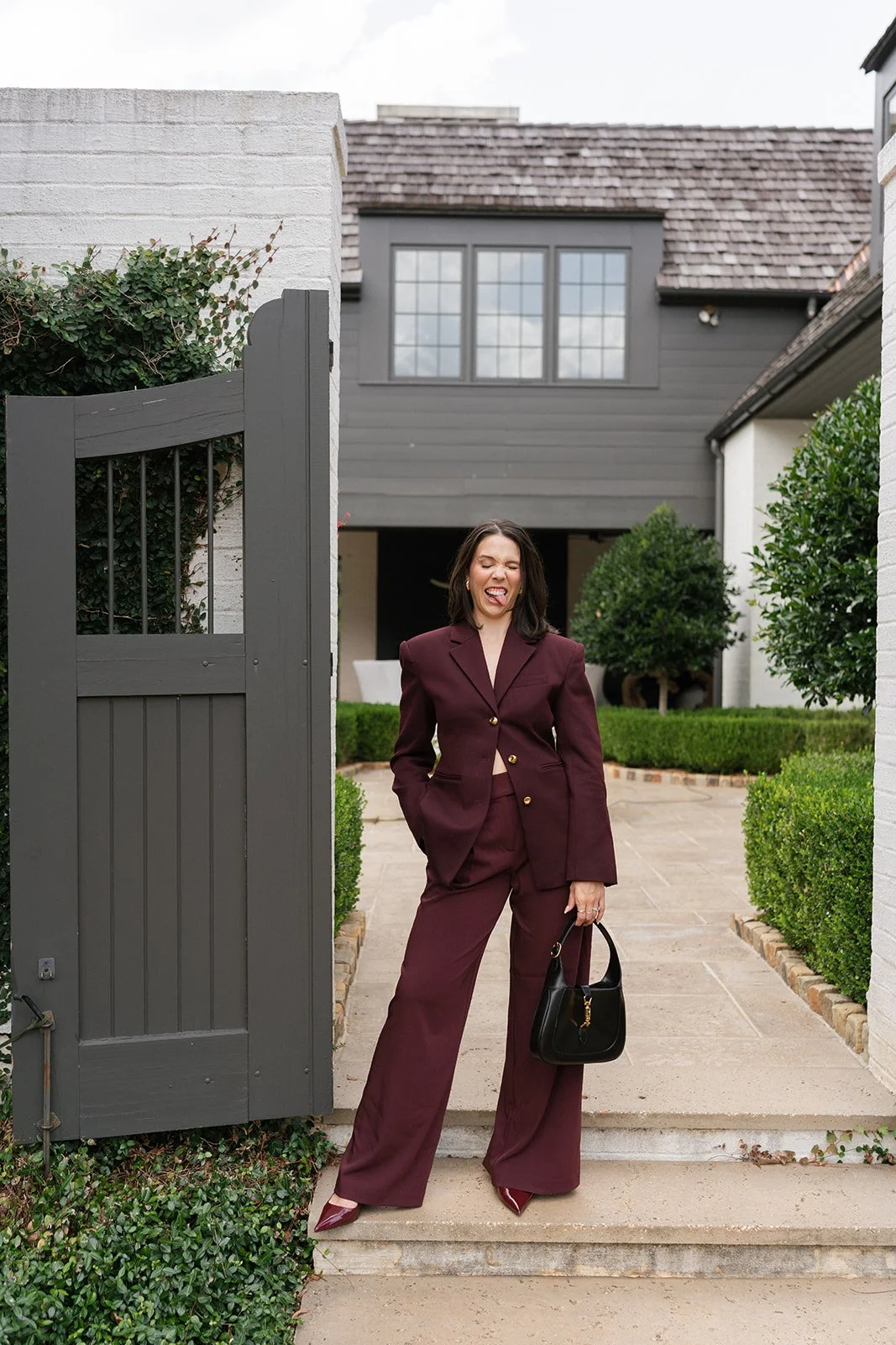 Editorial portrait of Carly Marie in a burgundy suit outside modern venue in Charlotte