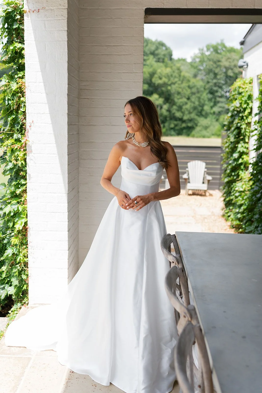 Bride posing on porch in strapless gown with soft bridal glam makeup