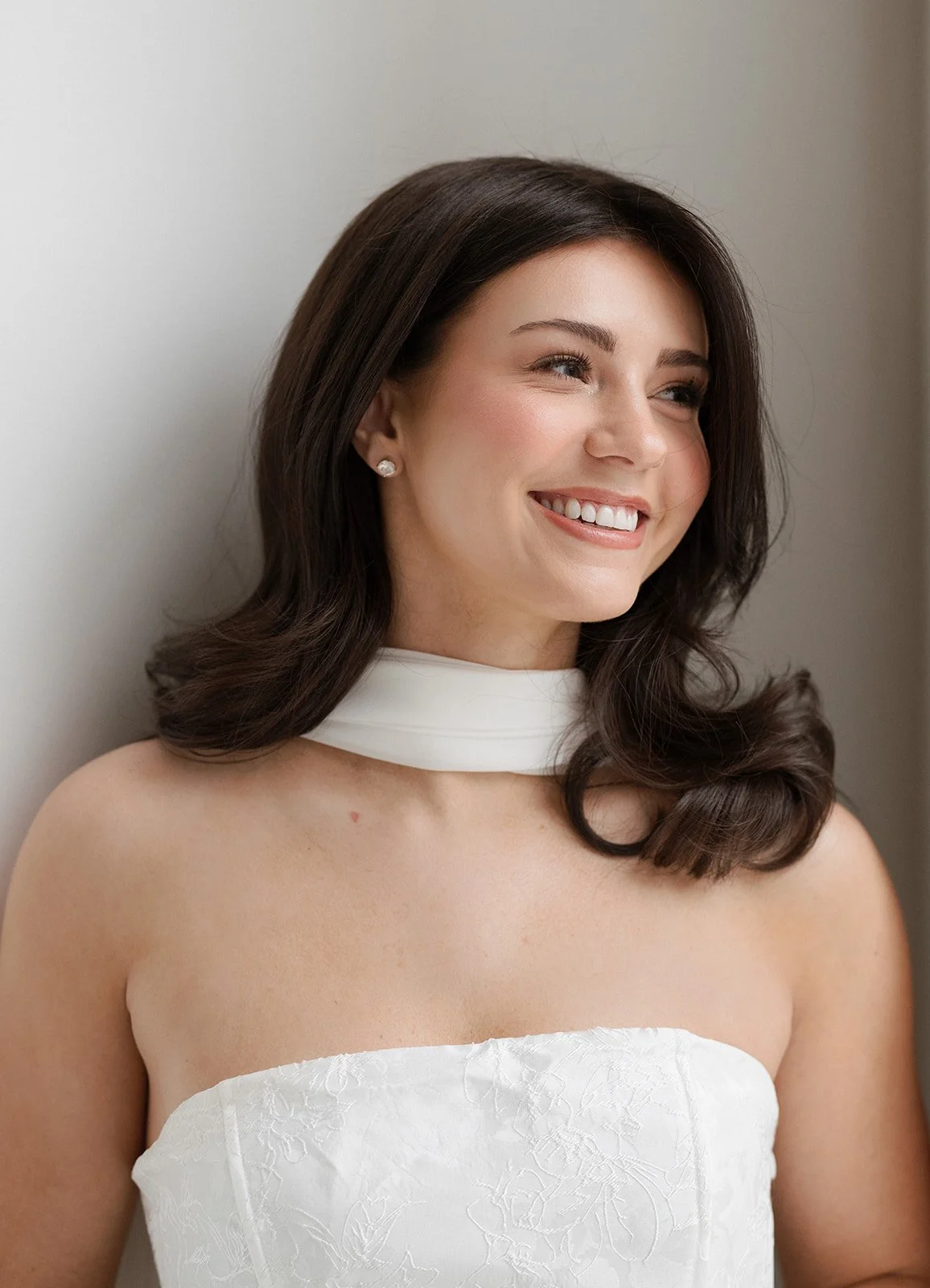 A woman in a white dress smiling before getting married. Bridal hair and makeup by professional makeup artist, Carly Amico of Carly Marie Artistry, a makeup artist in Charlotte NC.