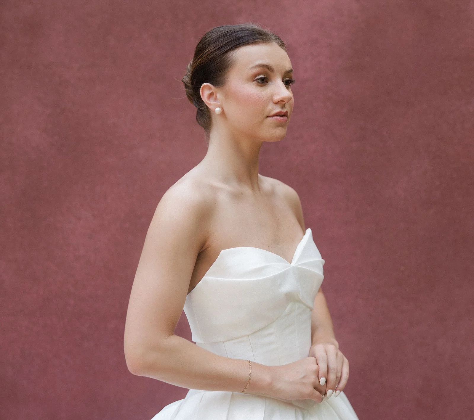A woman in a white wedding dress poses for a photo. She has a slick back bridal bun and soft glam makeup that looks natural. Bridal hair and makeup by professional makeup artist, Carly Amico of Carly Marie Artistry, a makeup artist in Charlotte NC.