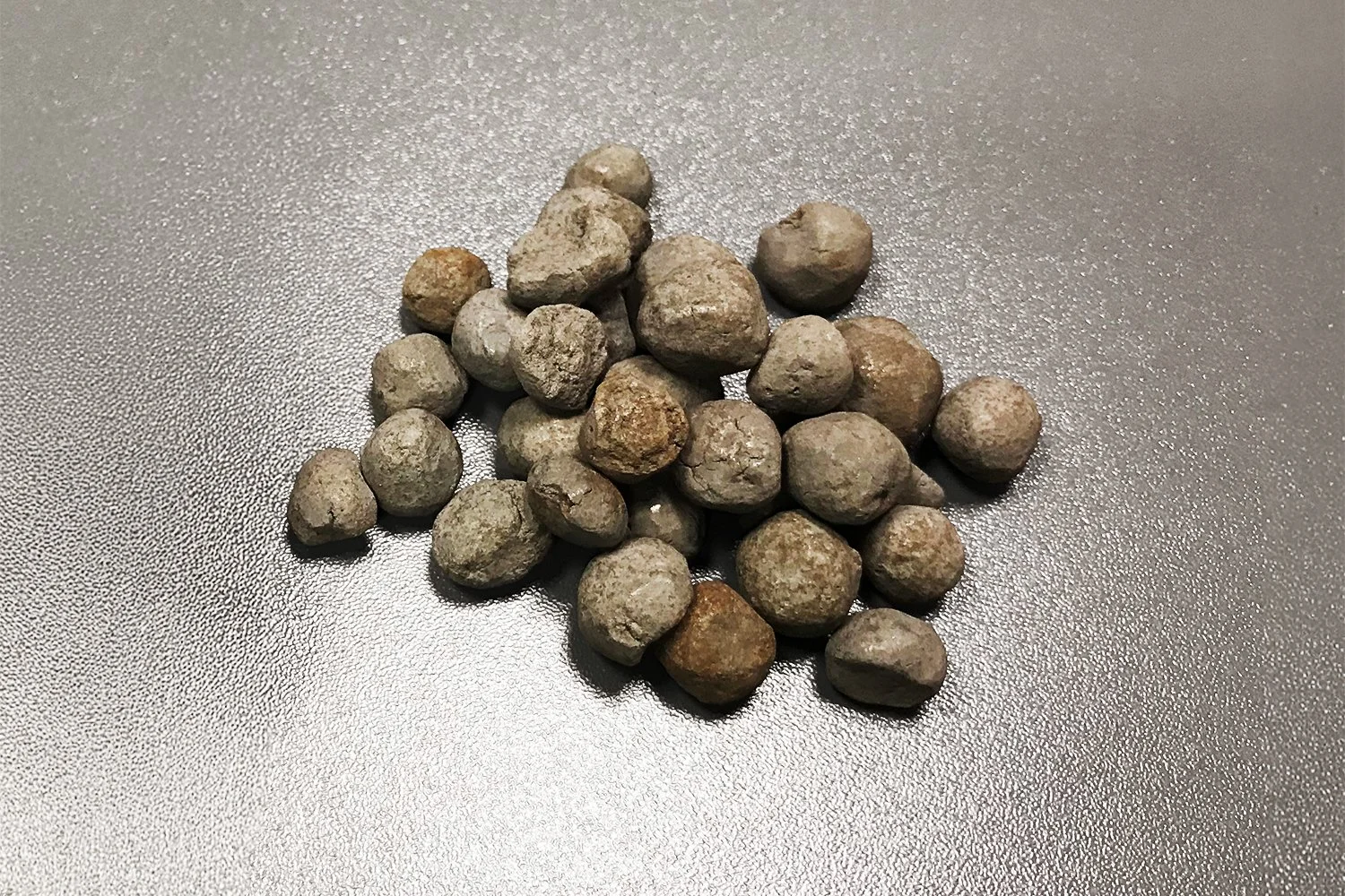 A group of small, irregularly shaped rocks on a gray textured surface.