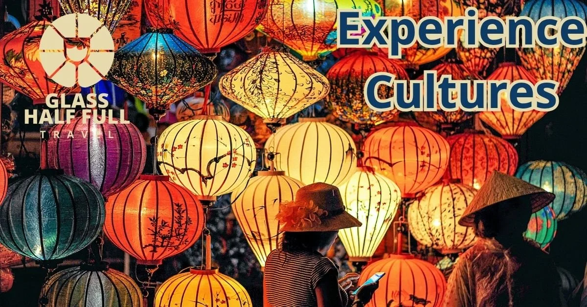 Colorful paper lanterns hanging at night, with two women wearing traditional Asian conical hats in the foreground.