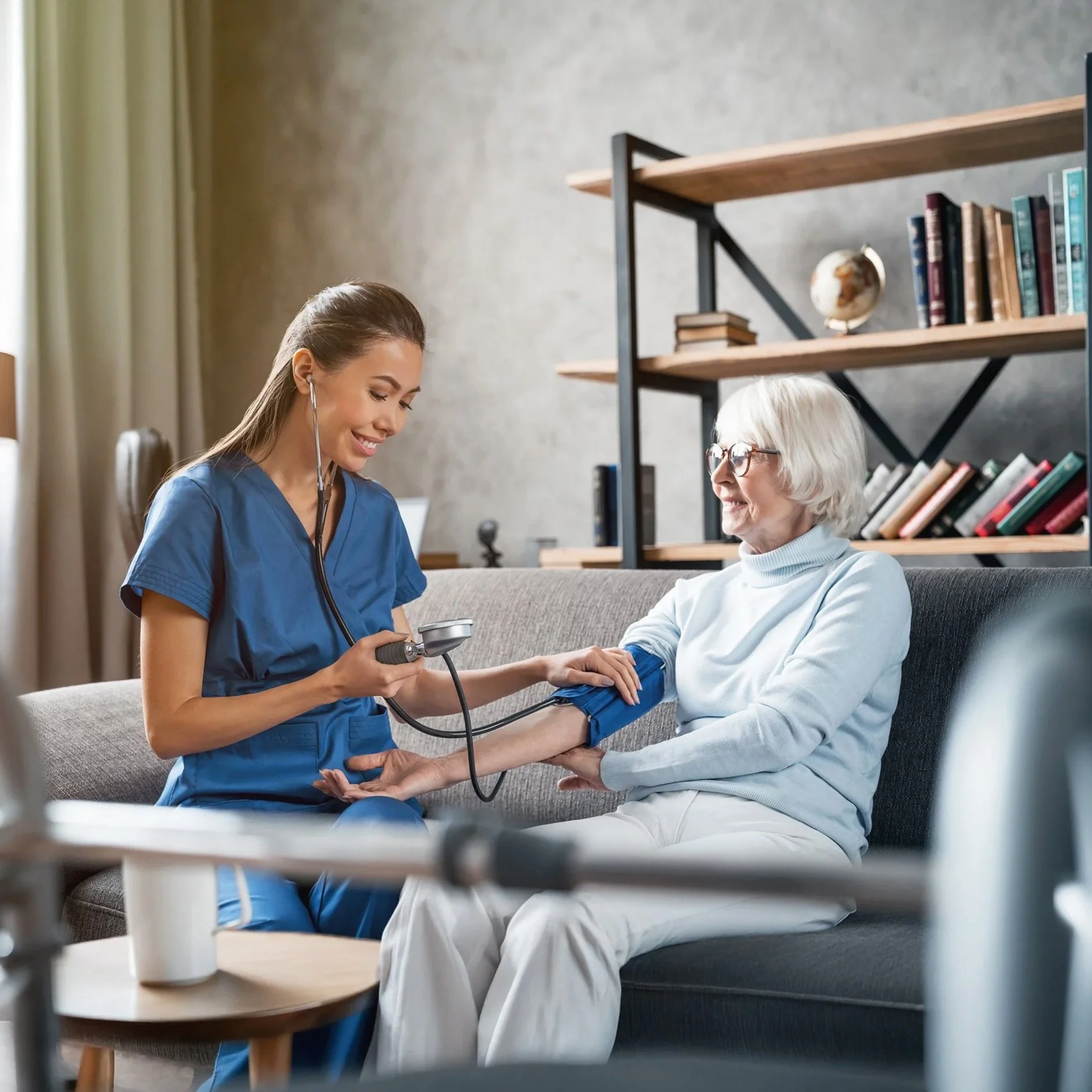 A nurse taking a senior woman's blood pressure in a cozy living room.
