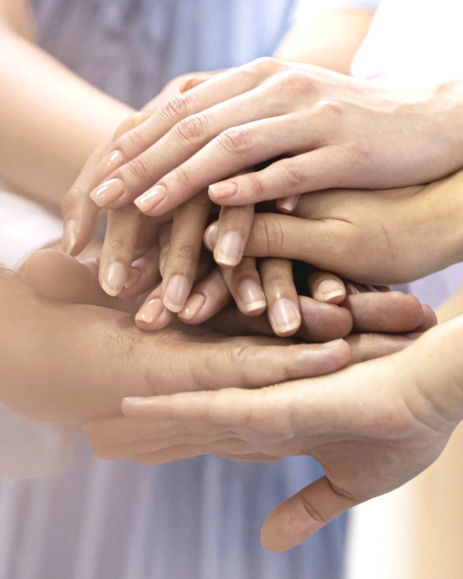 Multiple hands stacked together in a show of unity or teamwork.
