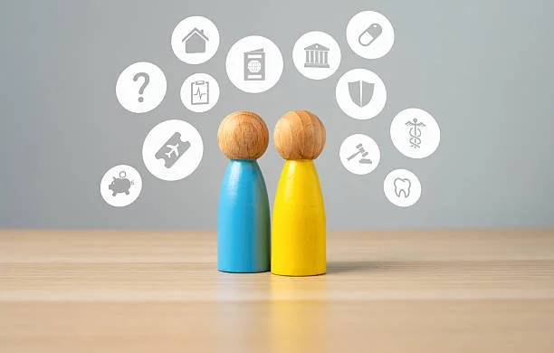 Two wooden peg dolls, one painted blue and the other yellow, on a light wooden surface with digital icons representing healthcare, finance, travel, law, and other fields floating above them.