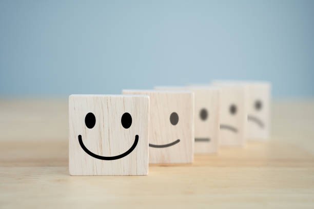 A row of five wooden blocks with smiley faces showing different emotions, from happy to sad.