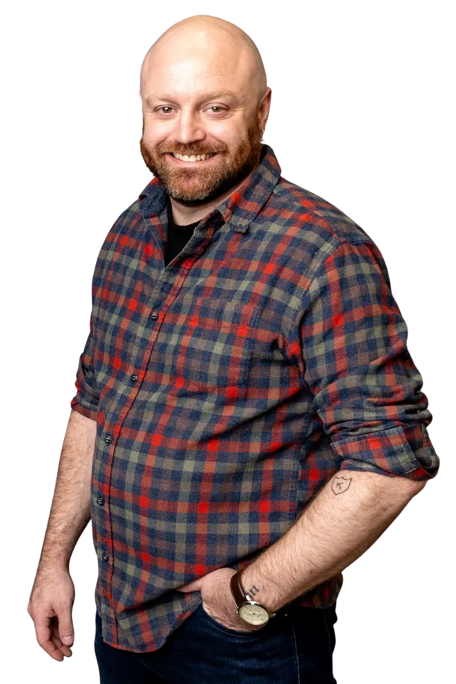 Josh Mittness wearing a plaid shirt and a wristwatch, standing with one hand in his pocket.