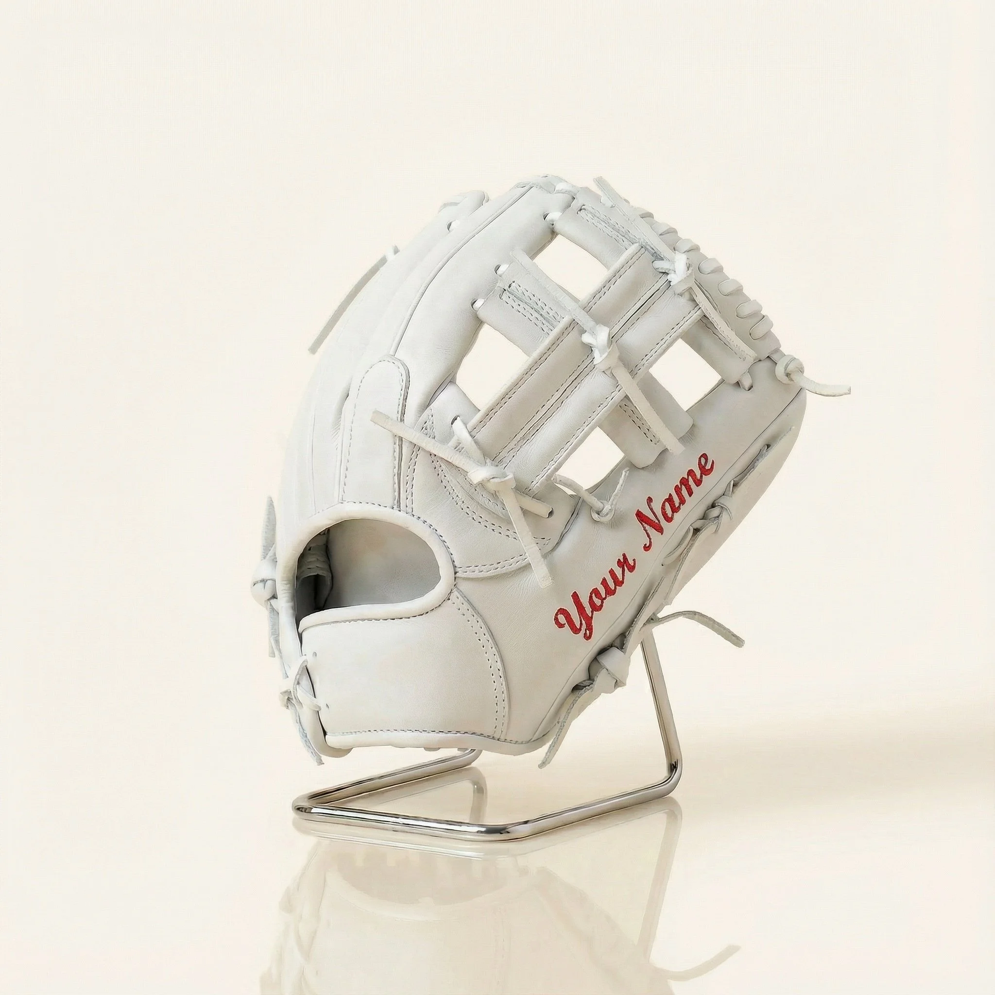 White baseball glove with red embroidery that says 'Your Name' on a metal stand against a plain light background.