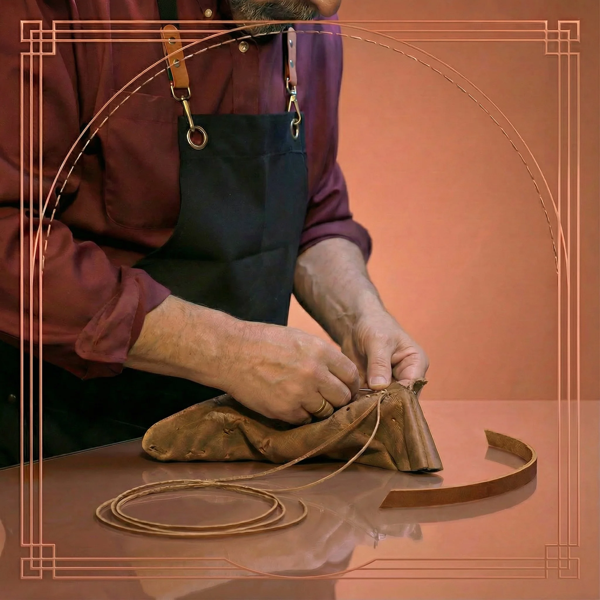 A person wearing a black apron and a burgundy shirt working on a piece of leather, stitching and shaping it on a wooden surface.