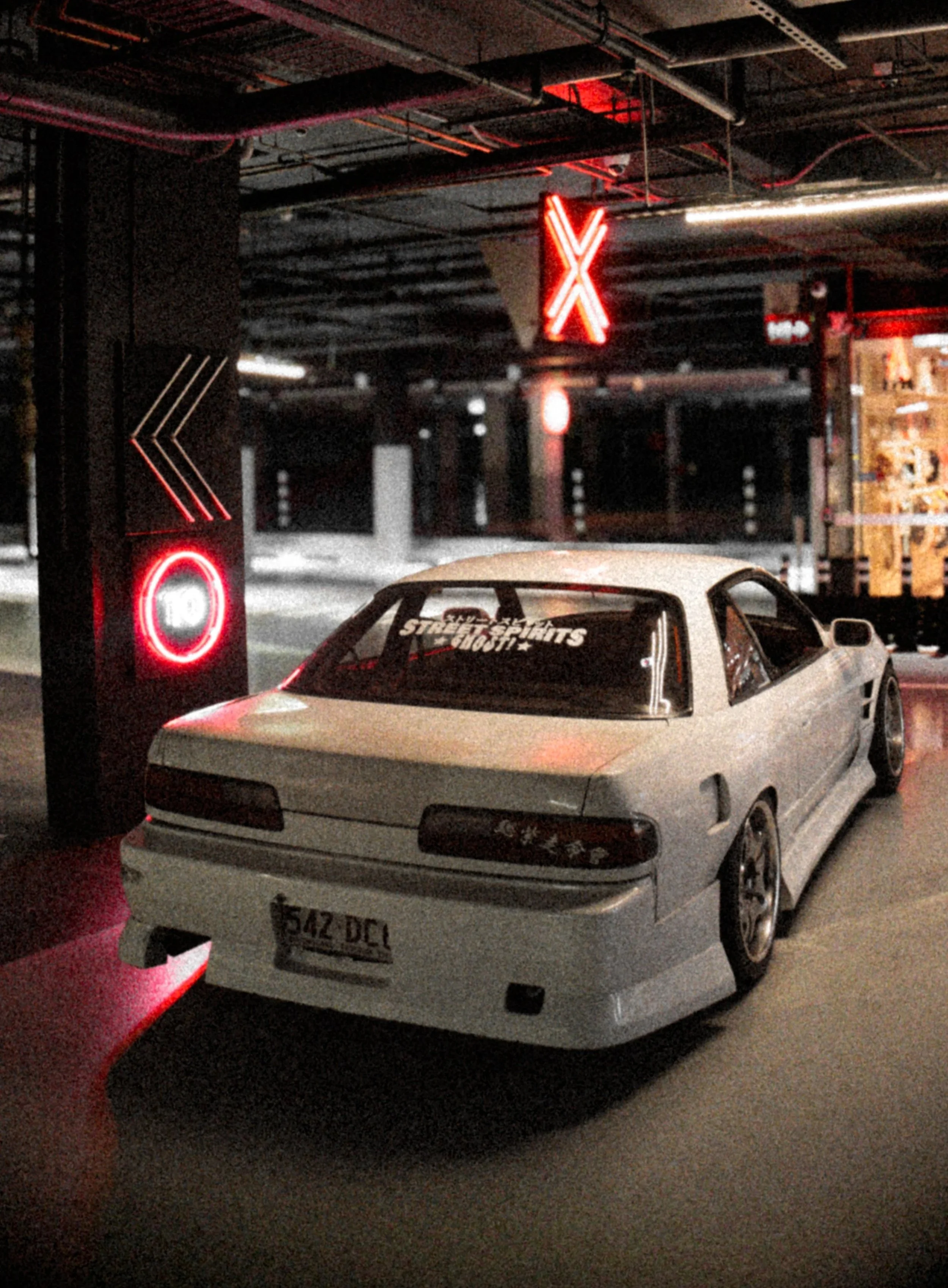 A white sports car parked in a parking garage with red neon signs and lighting