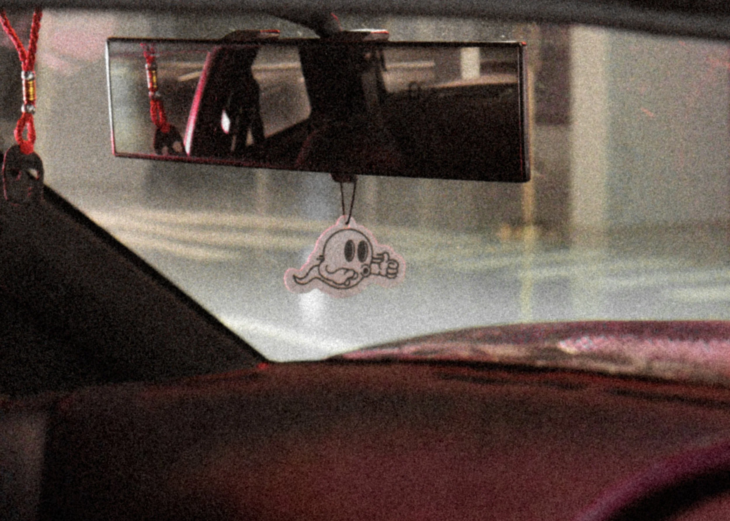 View of the inside of a car showing a hanging Ghost character keychain from the rearview mirror mirror.