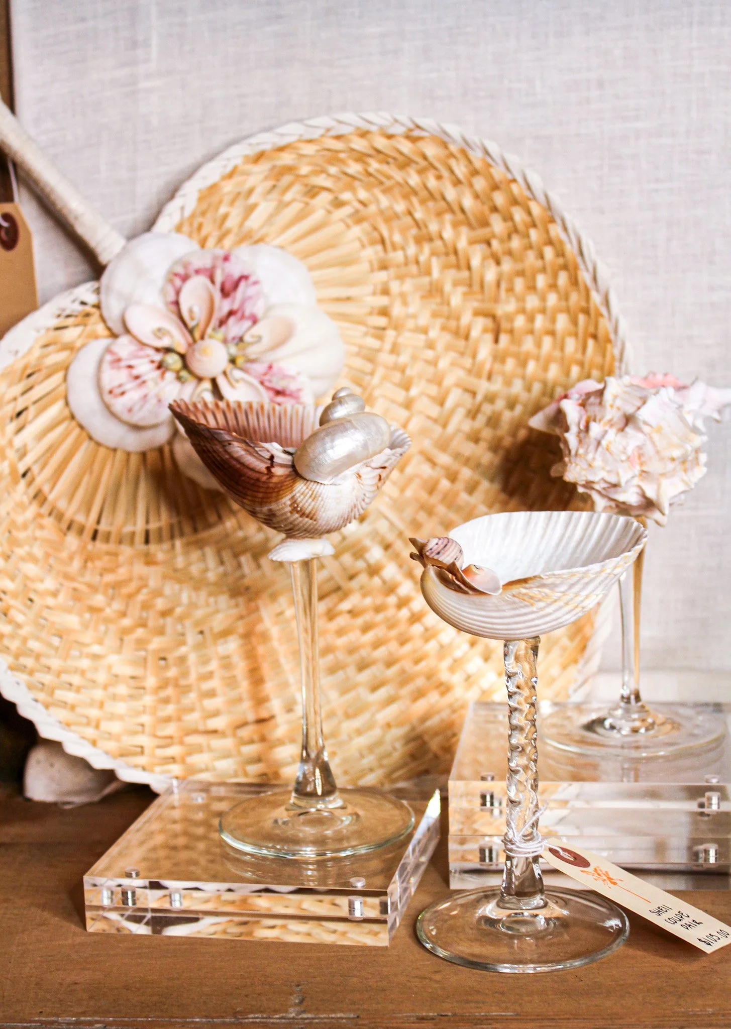Decorative display with seashells, glassware, and woven art pieces on a wooden surface