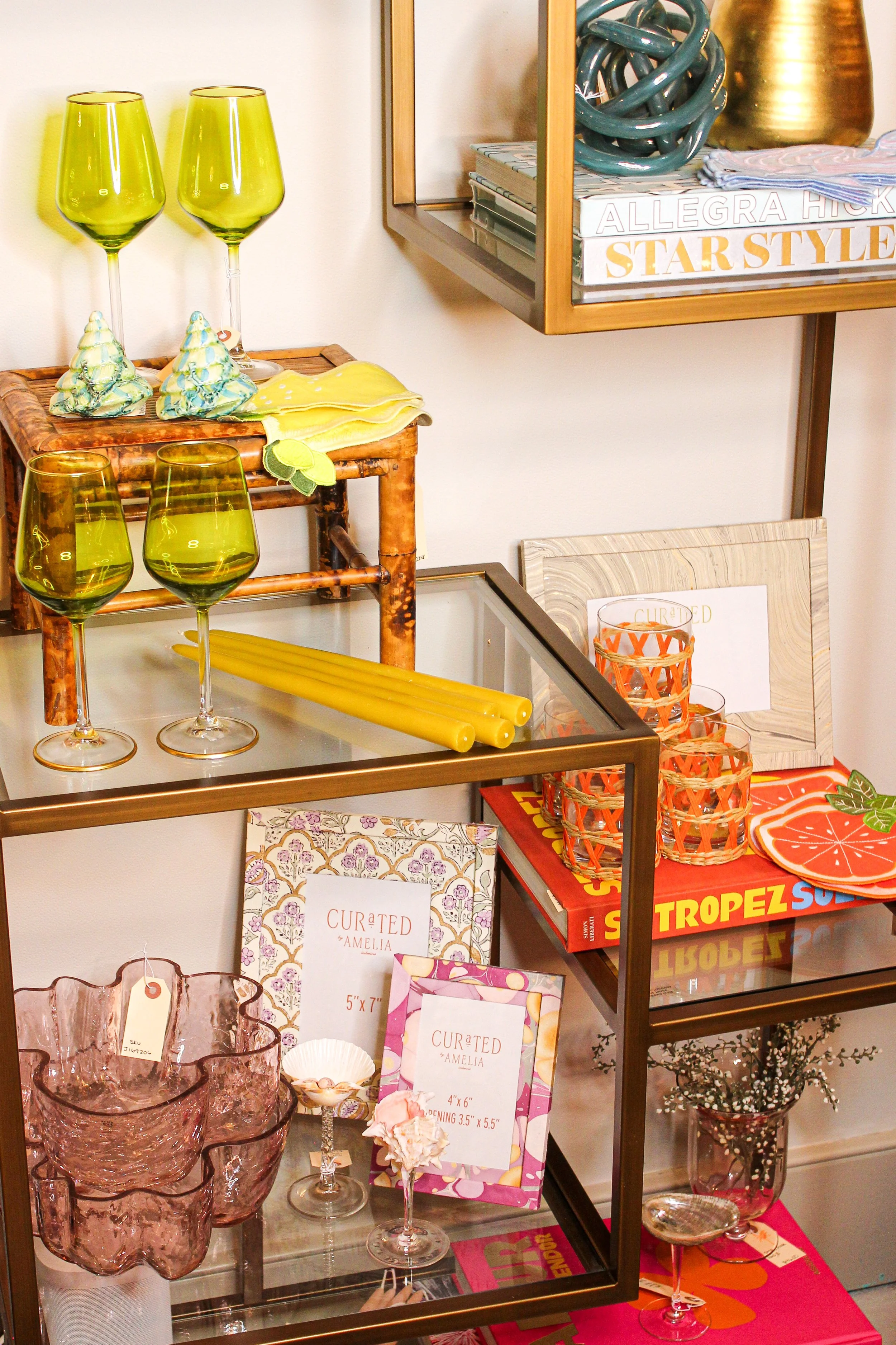 Decorative glassware, books, and home decor items on shelves and tables in a colorful display.