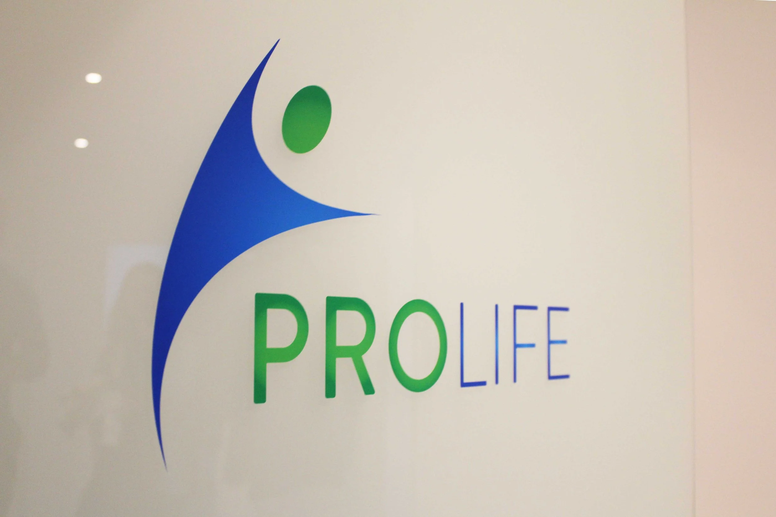 "ProLife" Logo auf weißem Hintergrund mit blauer und grüner Schrift und grafischem Element.