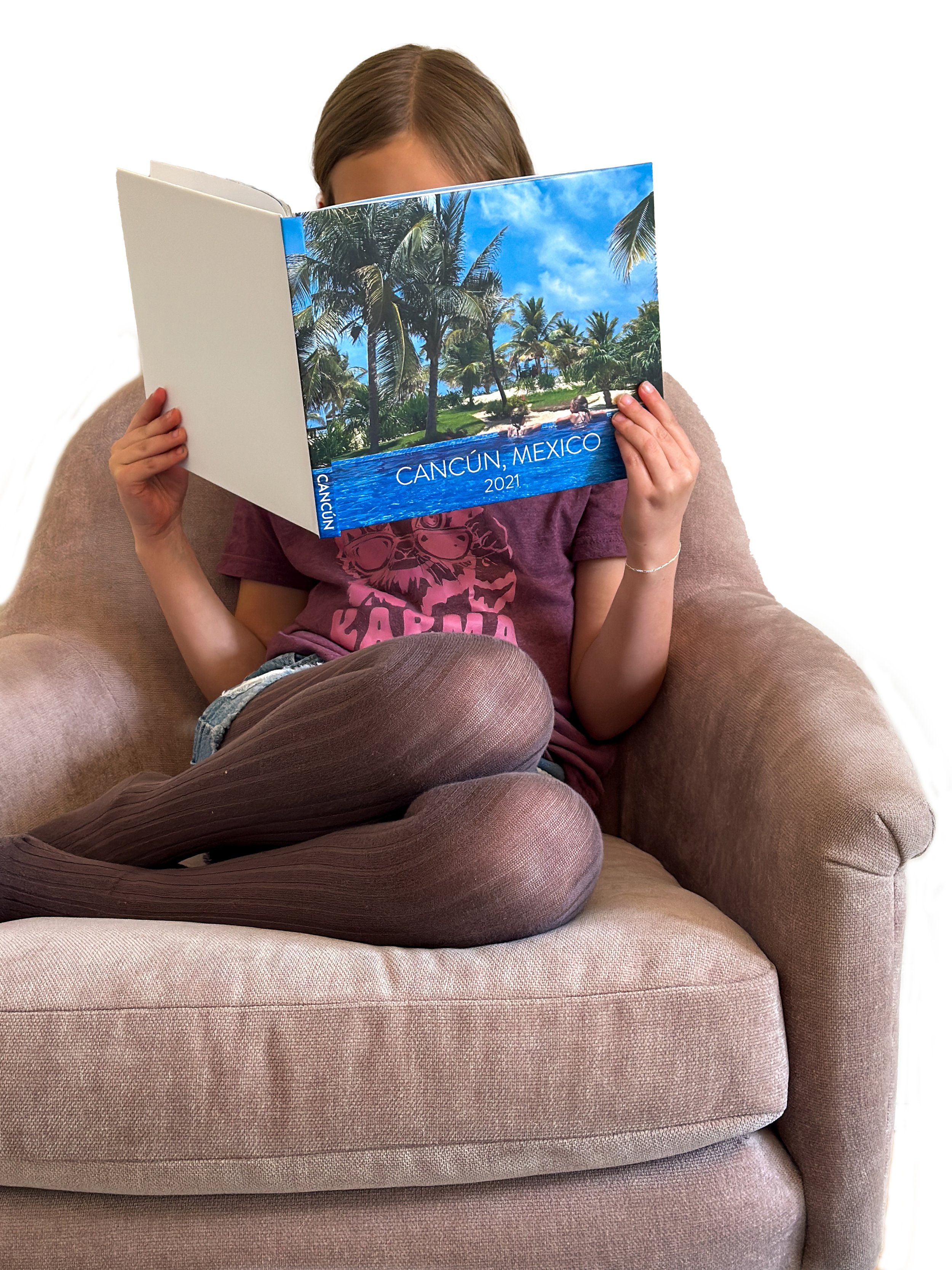 Girl reading a custom photo book from a vacation to Mexico, created by Forever Bound Studio